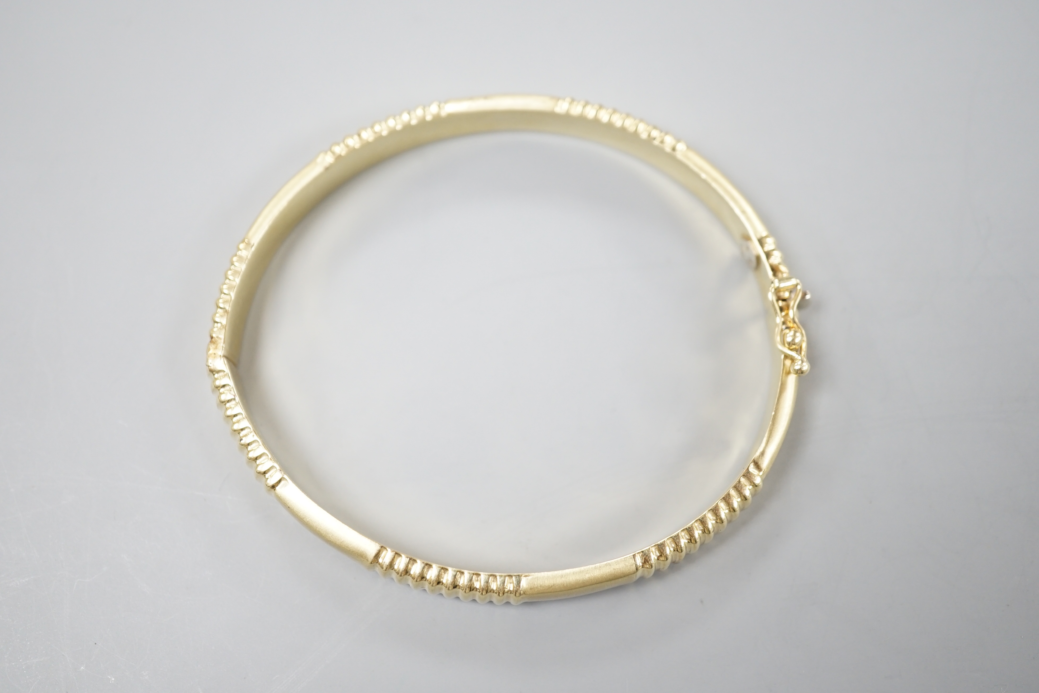 A modern 585 yellow metal hinged bangle, 12.8 grams.